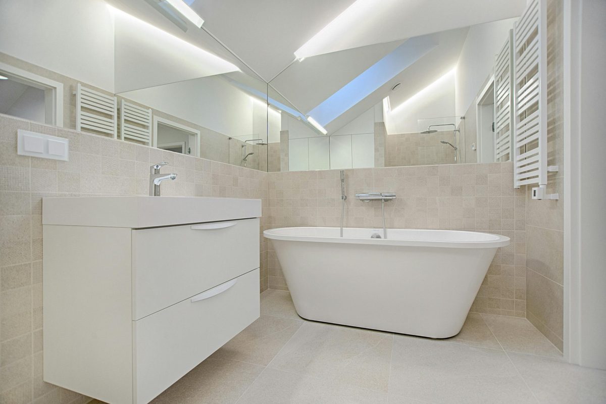 Elegant minimalist bathroom featuring a white bathtub and sleek fixtures.